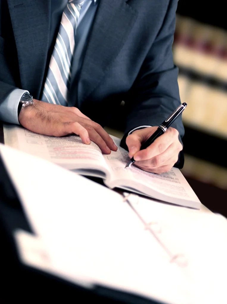 man writing in a book wearing a suit and tie