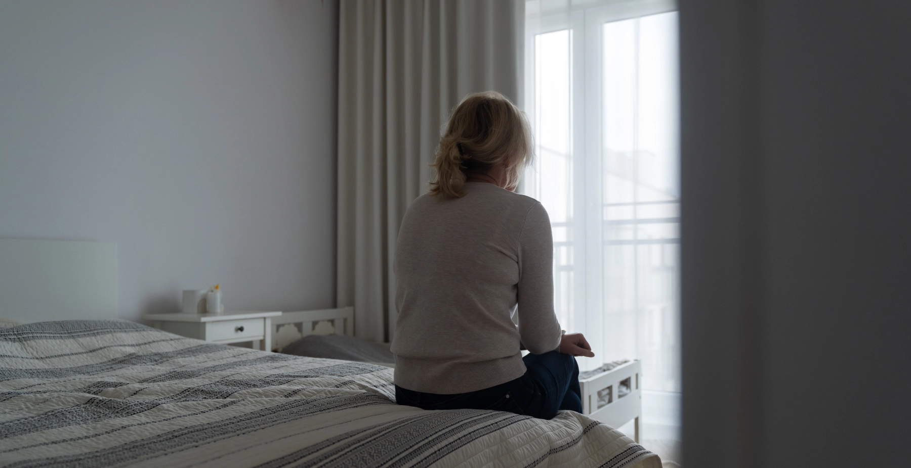elderly woman sitting on bed alone