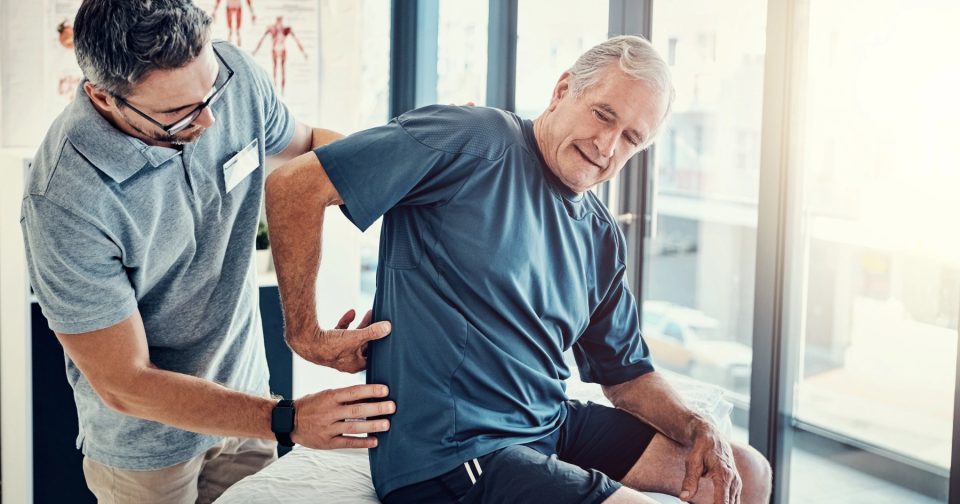 doctor feeling mans back while he points at it