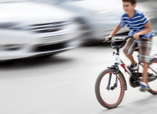 kid on a bicycle riding in front of cars