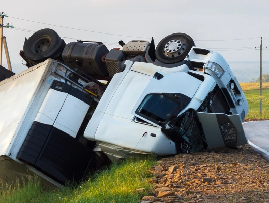semi truck flipped over on the side of the road